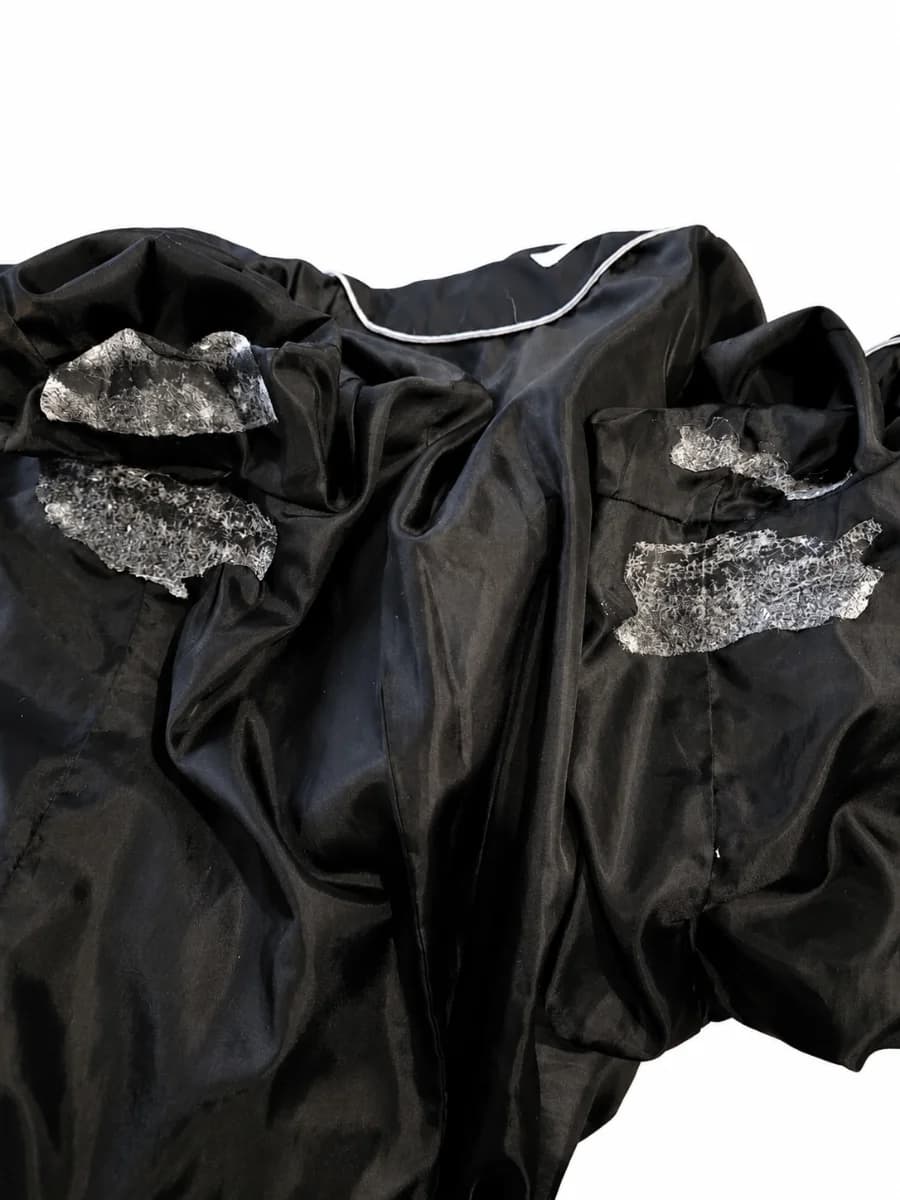 Fibrous adhesive residue visible at two points on a dark garment lining after removal of the documented BESARME samples.